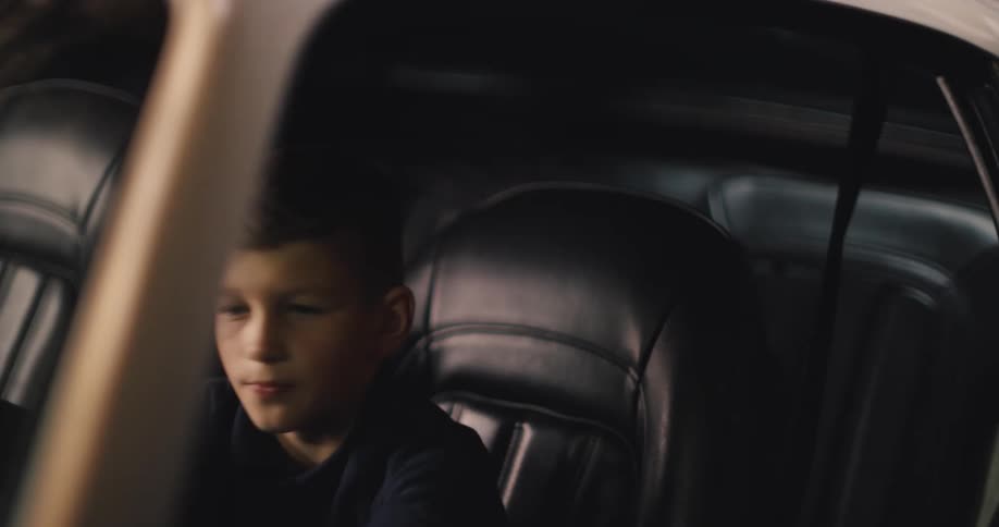 With a grin a young boy climbs behind the wheel of a classic car his imagination taking over as he happily pretends to be driving