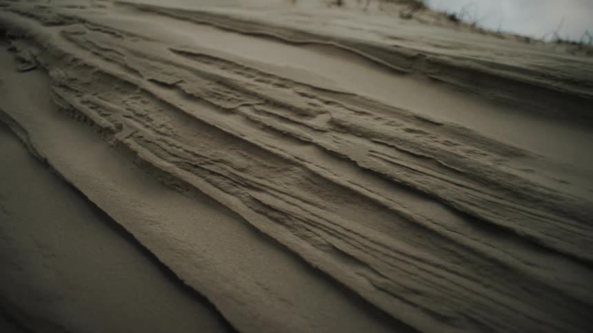 Intricate jagged layers of an eroded sand dune create a rhythmic and wind sculpted texture