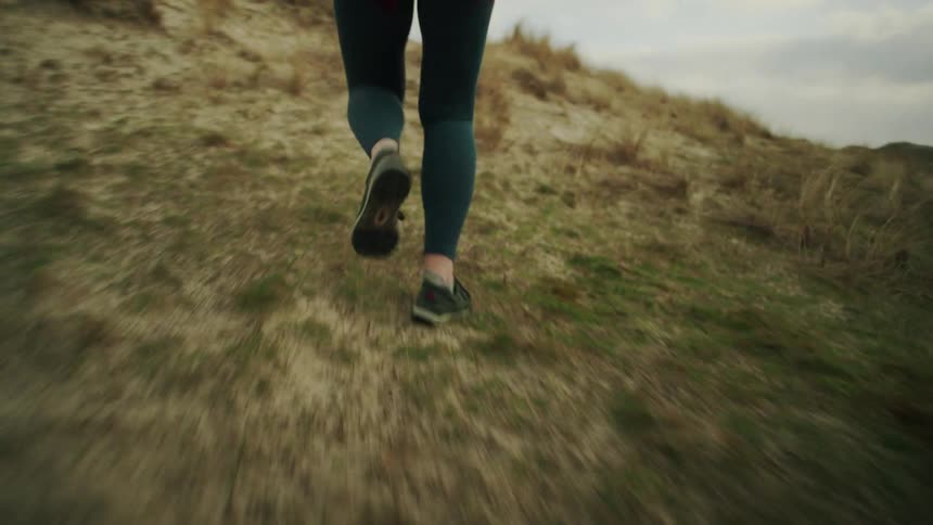 A woman running up a grassy hill