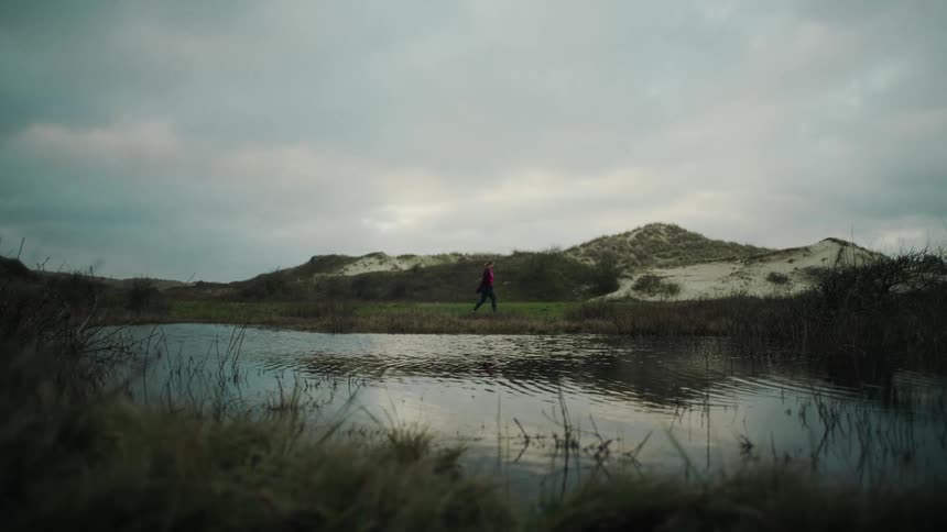 The person walks past the lake