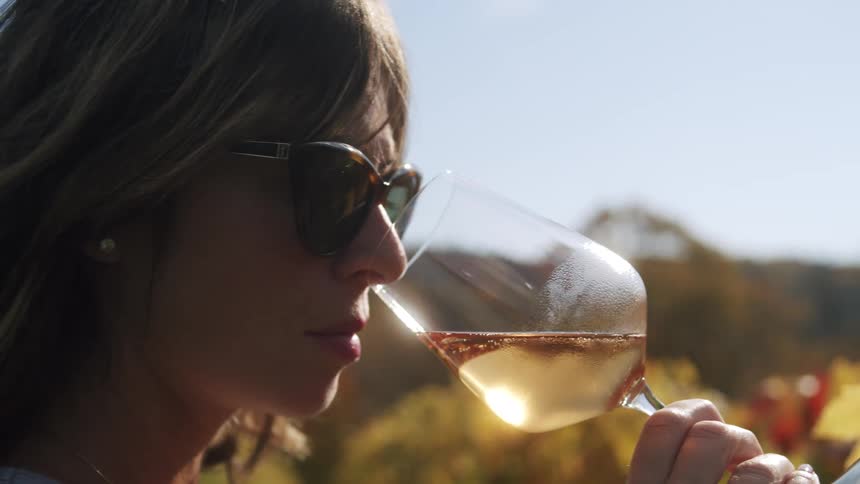 Woman at a winery tasting and smelling the aroma of ros wine in a glass