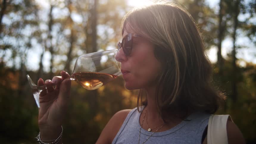 Woman standing outside of the woods drinking from a glass
