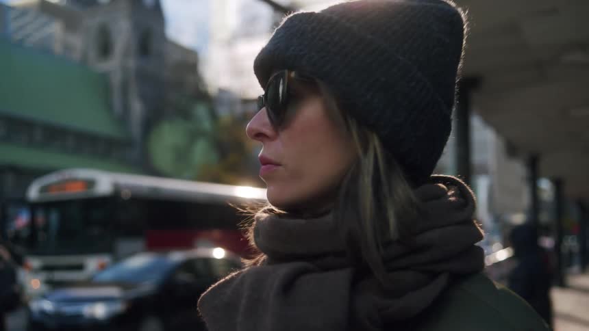The woman is standing on the street corner