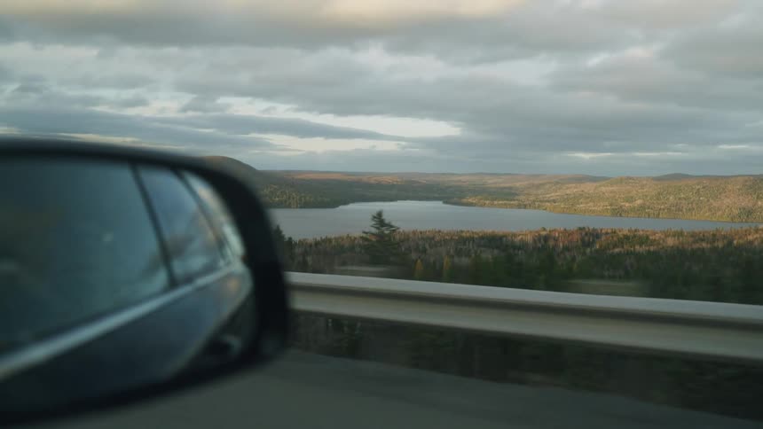 Landscape seen from a moving car with a lake and mountains in the background