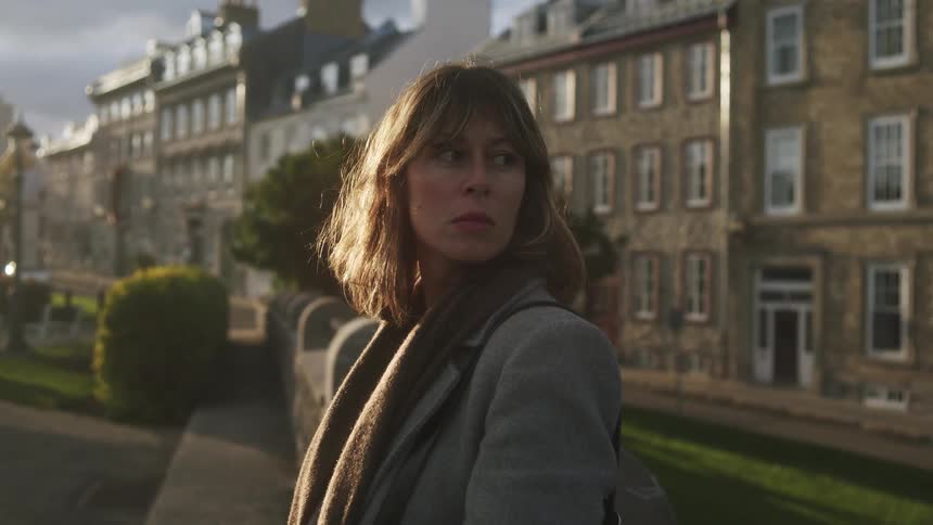 The woman looks back and forth in front of the apartments
