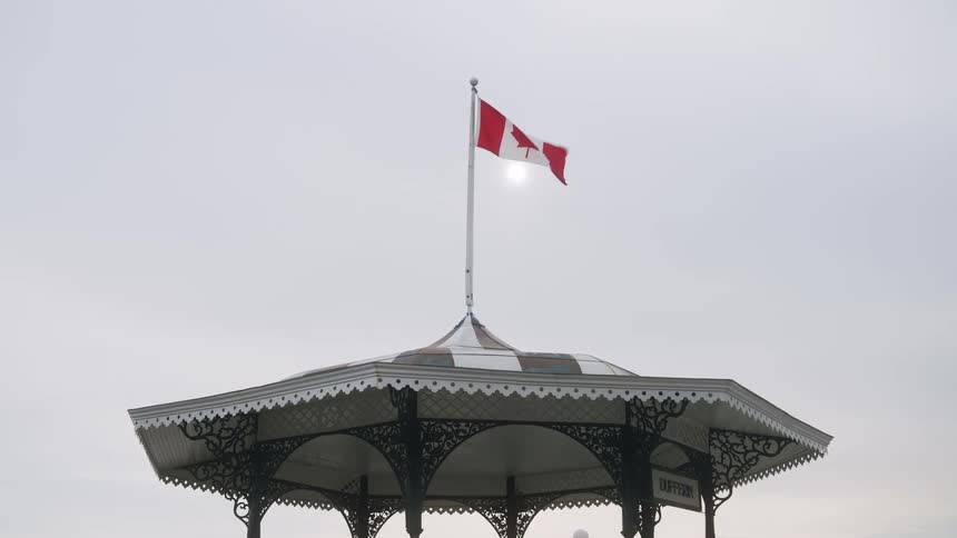 Canadian flag flying on top of a gazebo under a cloudy sky