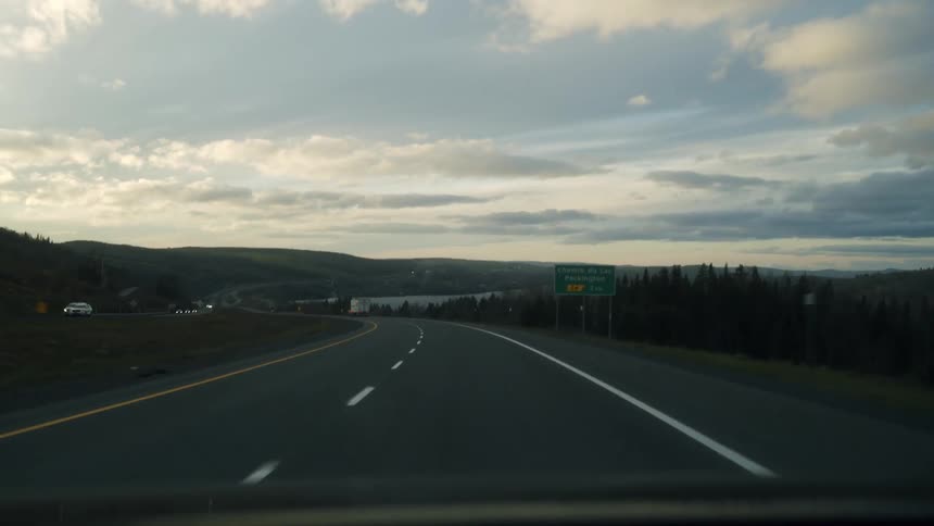 Highway surrounded by hills with sign indicating exit to packington