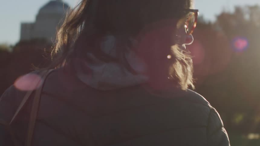 The woman is walking through the park
