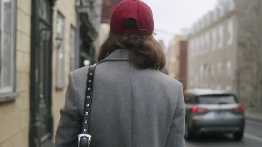 Woman in a red cap walking through an urban city
