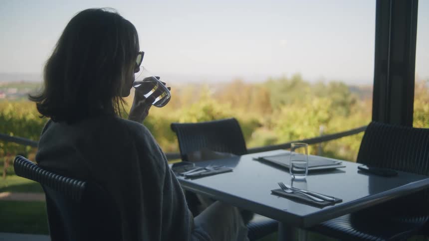 Woman sitting at a table drinking a glass of water