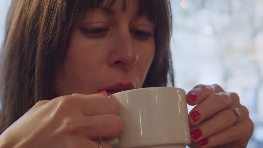 A woman drinking beverage from a white mug at daytime