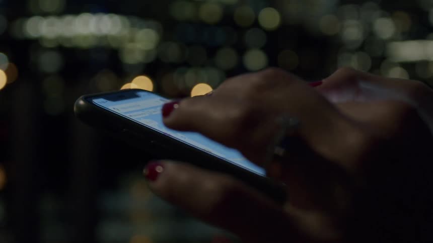 The woman is sliding on her cell phone