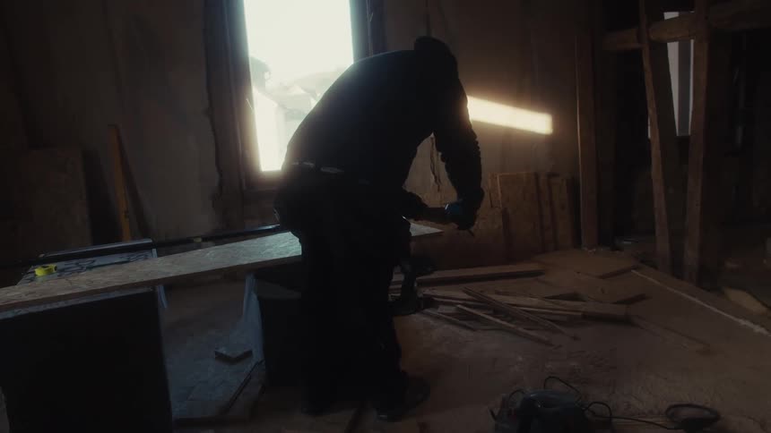 A carpenter working on a shelf inside a garage at midday
