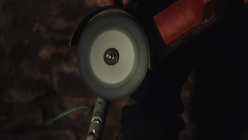 Metal pipe being cut with sparks highlighted against dark background