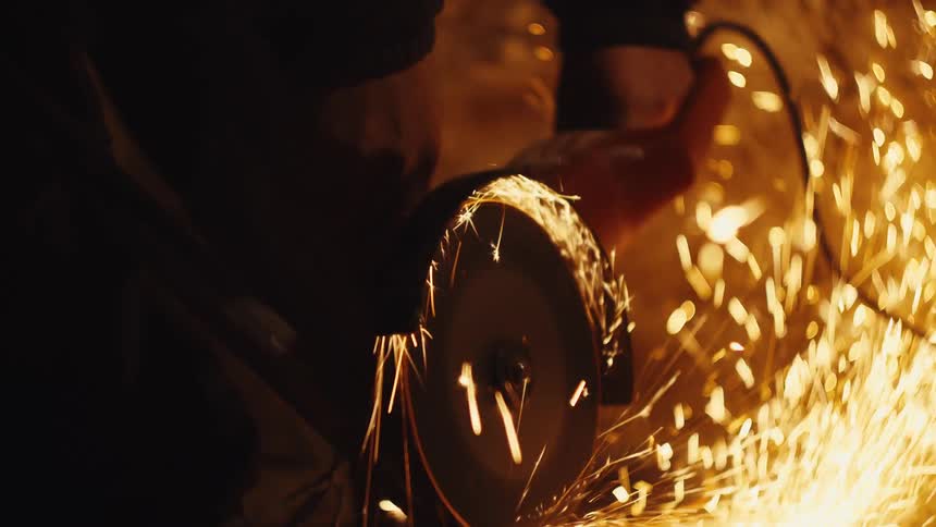 Electric cutting tool produces intense sparks while working on metal in an industrial environment
