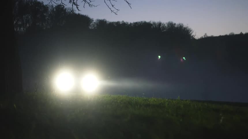 Suv with headlights on road at dusk