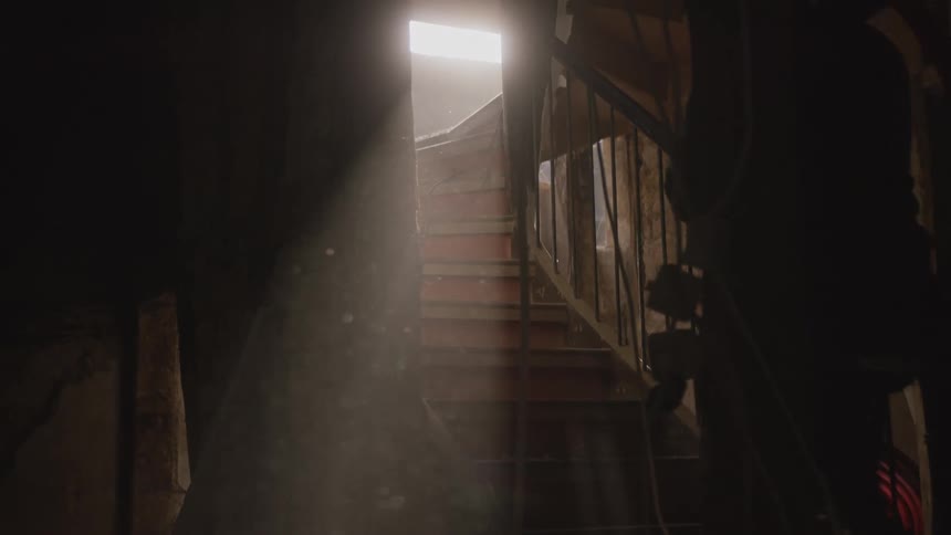 The man carries a hose up the stairs in the basement