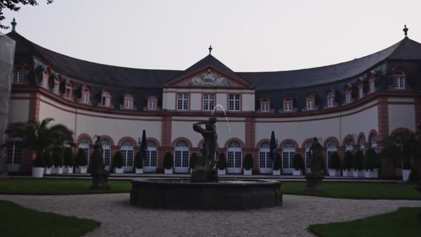 Semicircular classical building with central fountain and symmetrical surrounding gardens