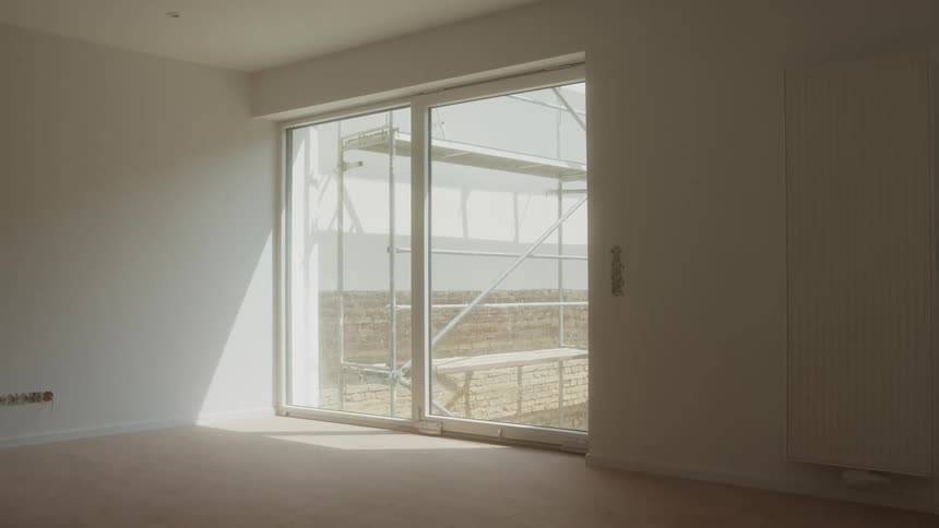Empty room with sliding glass door and scaffolding visible outside
