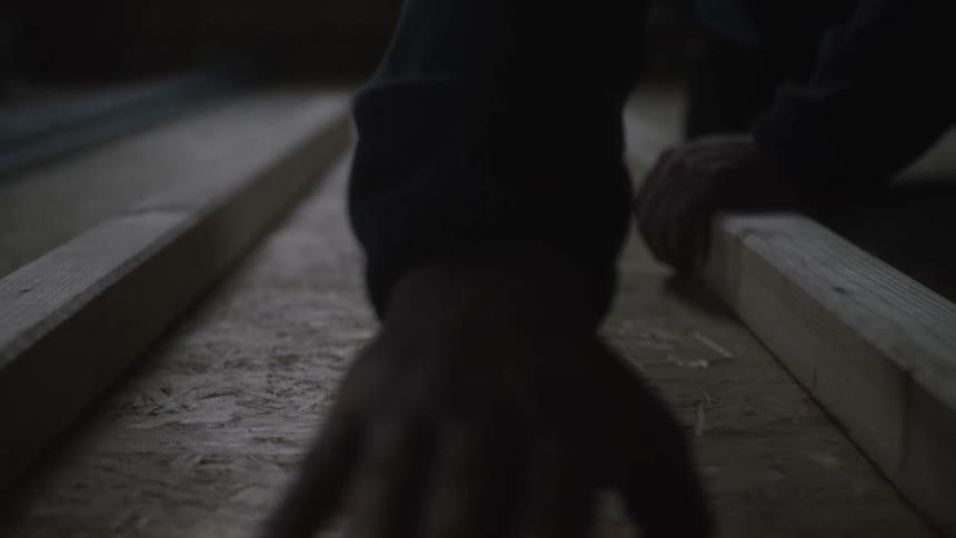 Hands aligning wooden planks on osb surface in carpentry setting