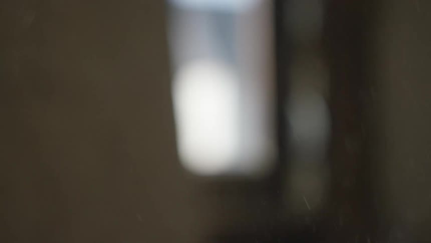 Tiny particles of dust float through a soft beam of light in a dark interior space the camera uses a shallow depth of field creating a dreamy and quiet atmosphere