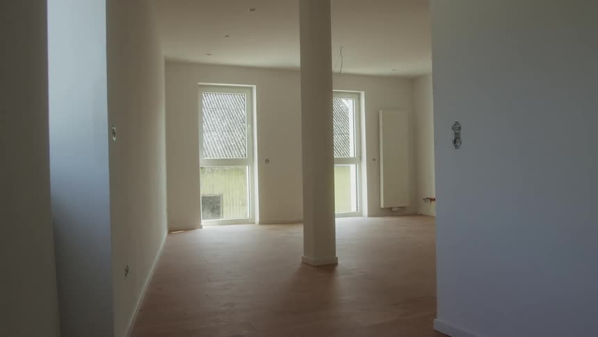 Unfurnished residential space with wooden floor and vertical windows lighting the area
