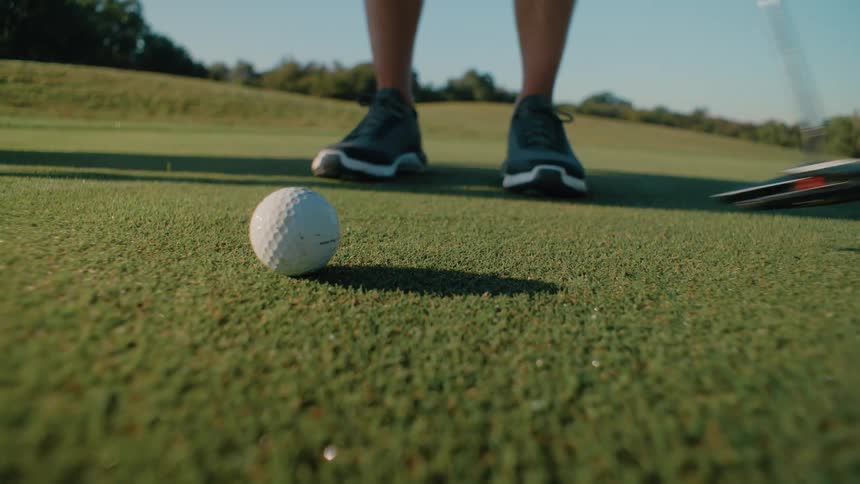 Person with a golf club positioned in front of the ball