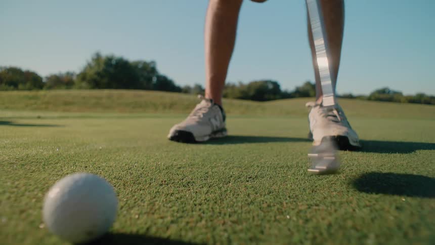 Person warming up with a golf club in front of a ball