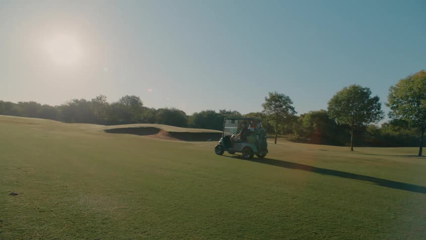 A golfer driving a golf cart across the golf course on a sunny day