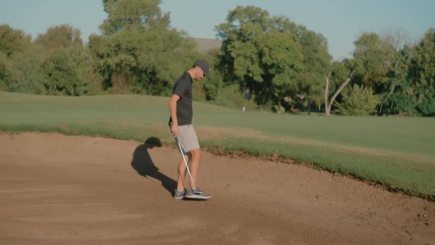 The golf player is playing from a sand trap