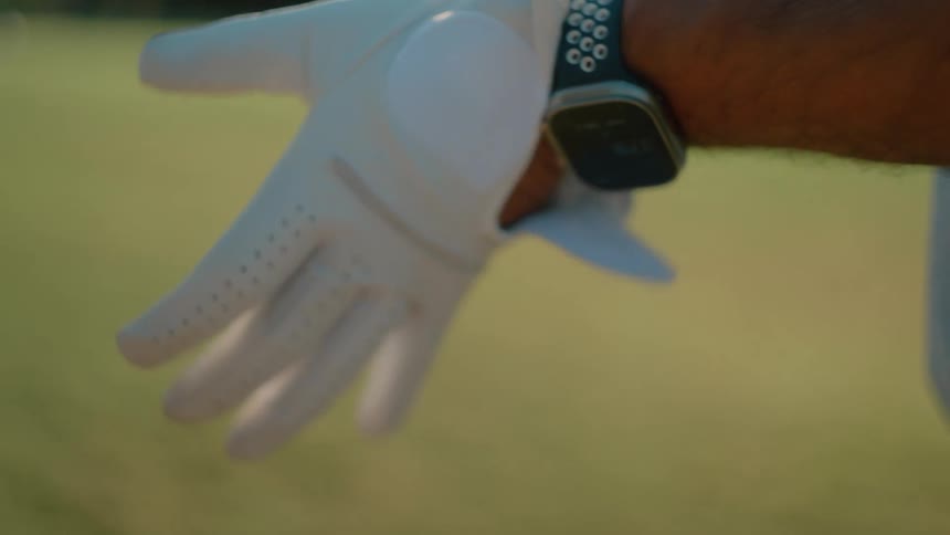 A man putting on a white golfing glove