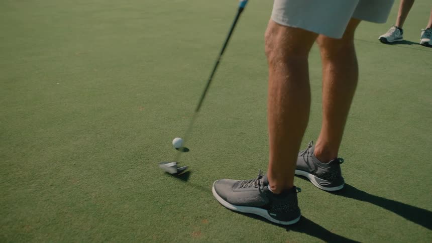 A man practicing putting on a sunny day