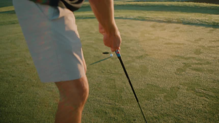 The man putts into the hole and then picks the ball up