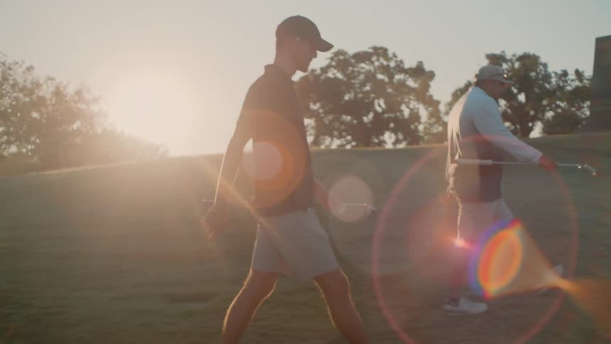 Two men are walking on a golf course