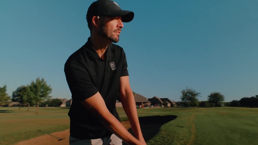 The man hits the golf ball on the course