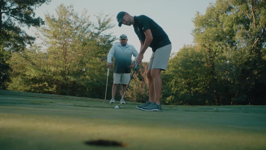 The man putts the golf ball towards the hole