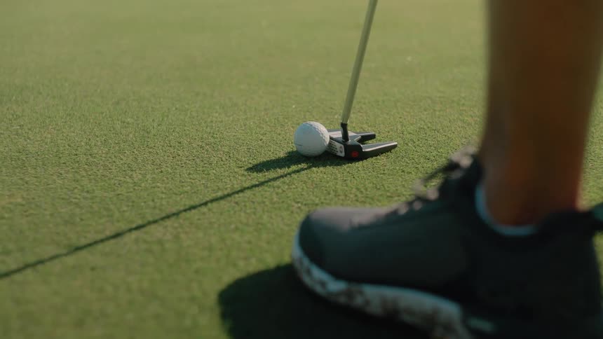 A person getting ready to put a golf ball