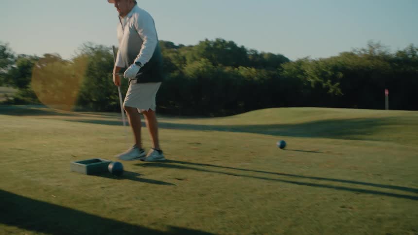 The man hits the golf ball then walks to the golf cart