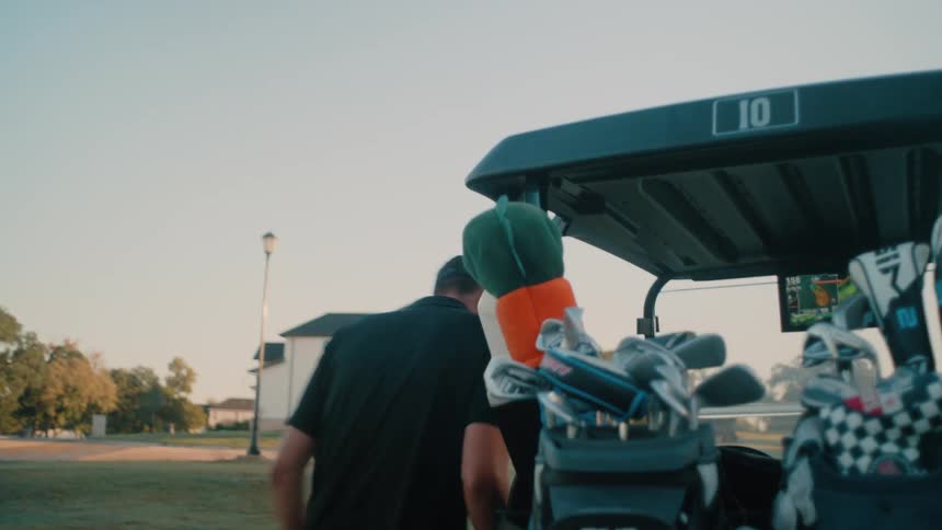 The men drive on the golf course with a golf cart