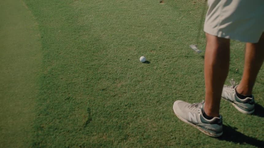 Person with a golf club near a golf ball on a course