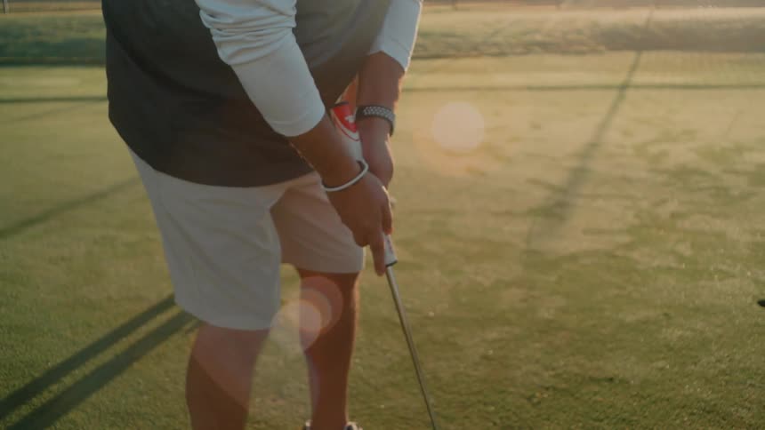 Golfer makes a light putt on the green with the putter close to the ball