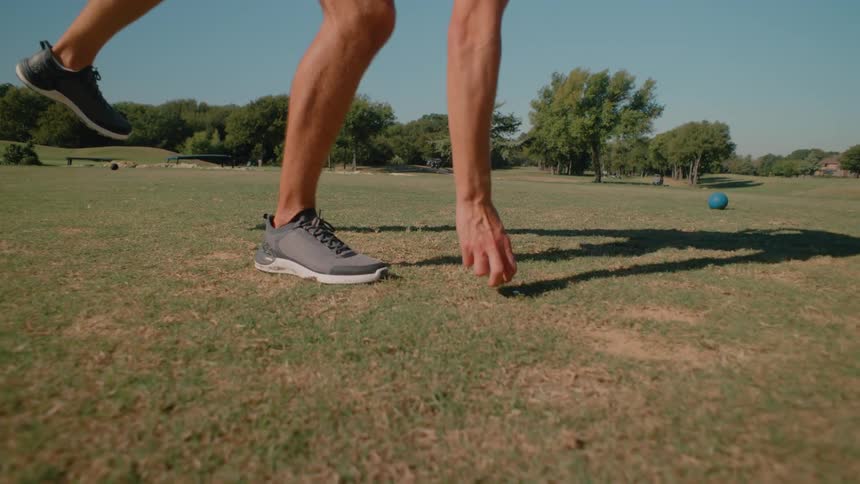 A person placing a golf ball and tee on the ground