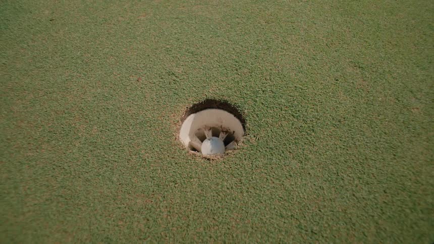 The man putts the ball to score