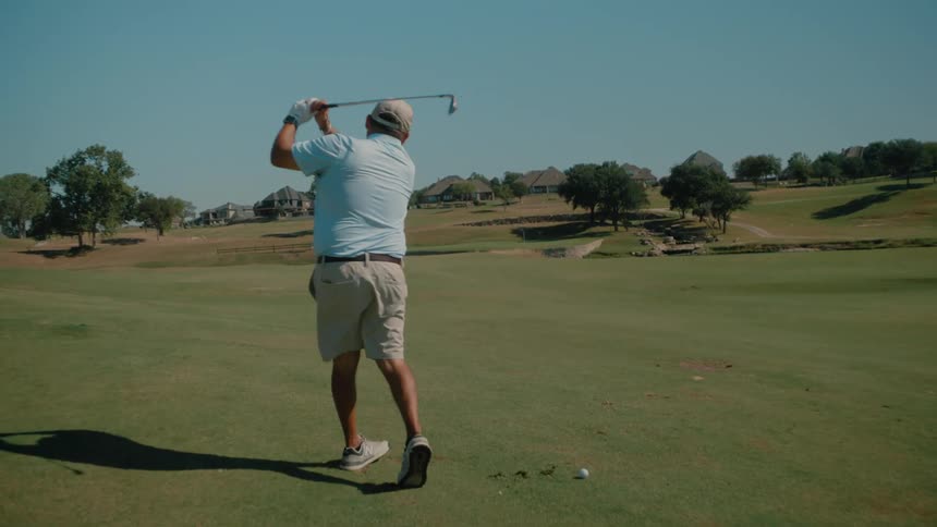 A man swinging a golf club to hit a ball