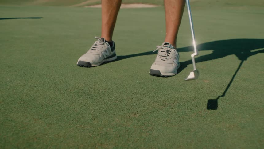 Man stands on the golf course and hits the ball with his golf club