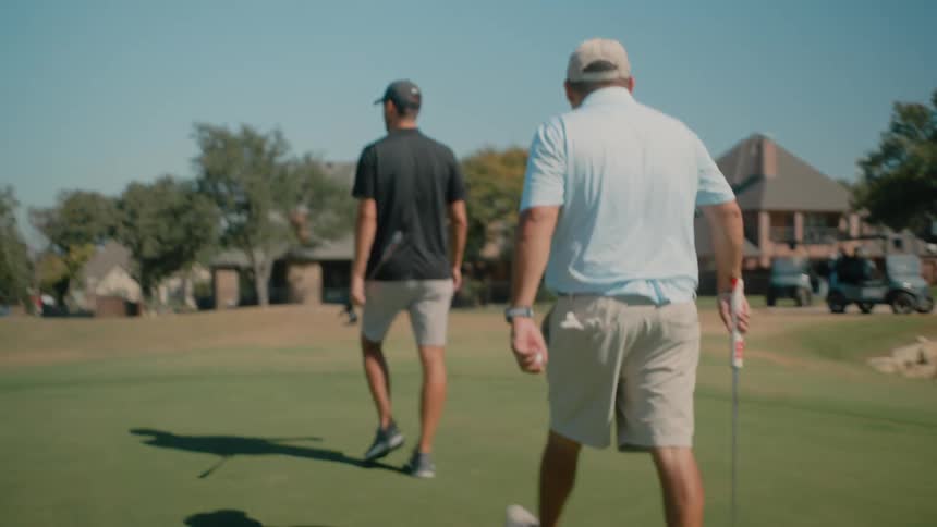 Two men carrying golf clubs on a golf course