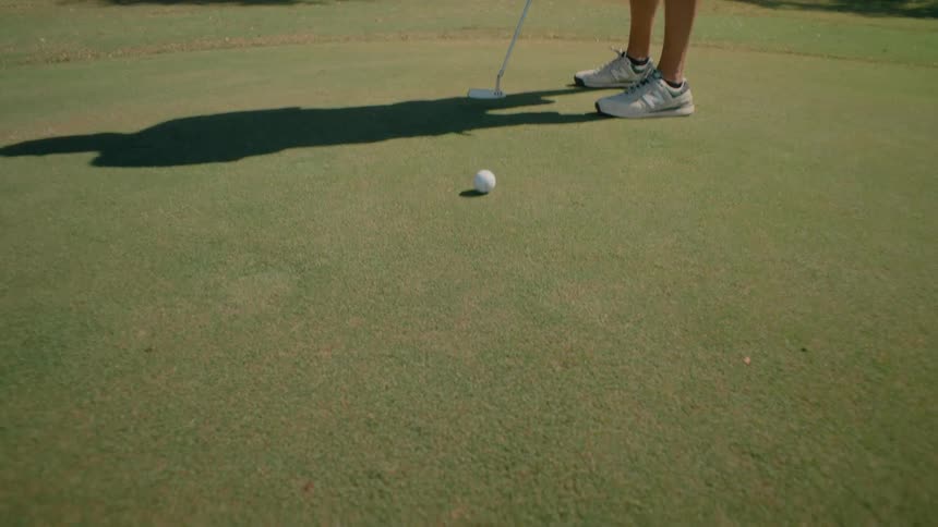 The golfer putts the ball on the green