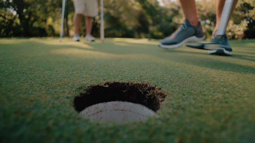 Two people playing golf the visual narrative centers on a missed putt from a groundlevel perspective