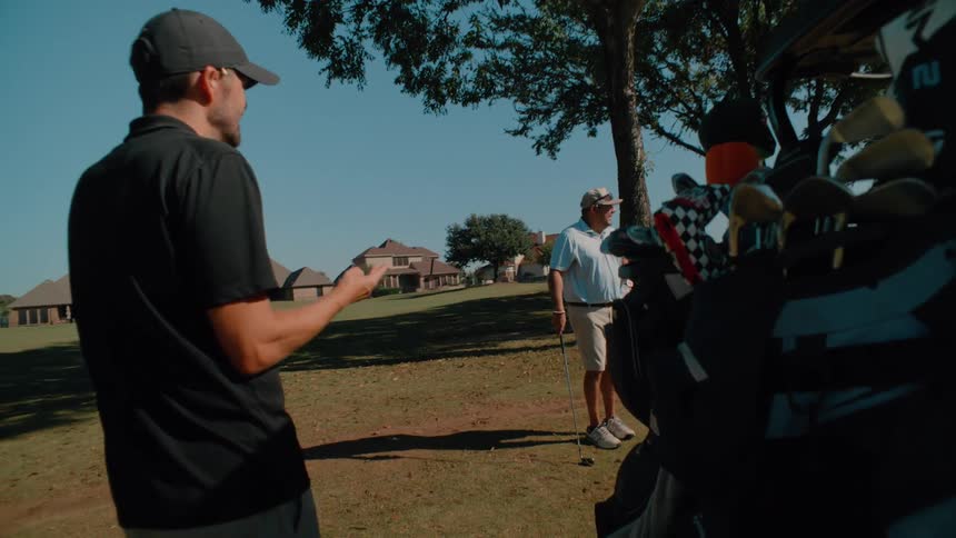 Two men in a field talking during a round of golf