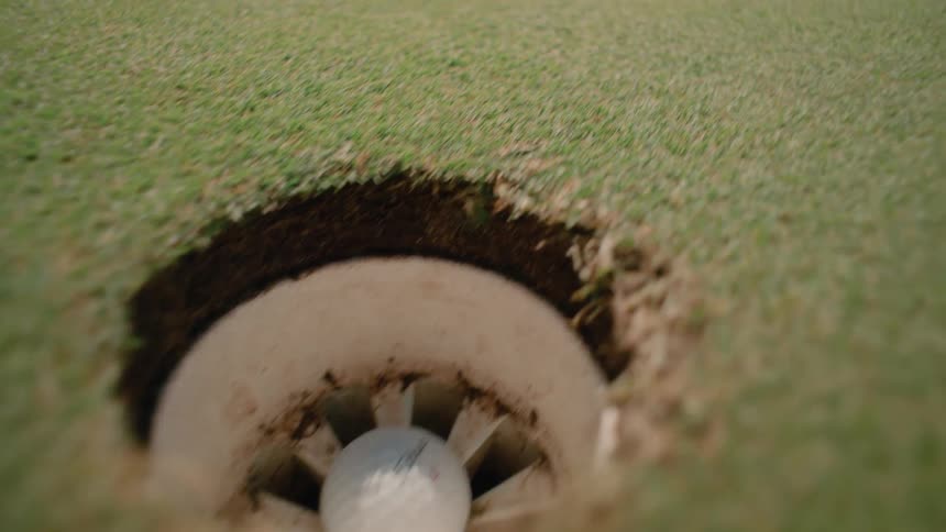 Ball hits the target and someone catches the golf ball